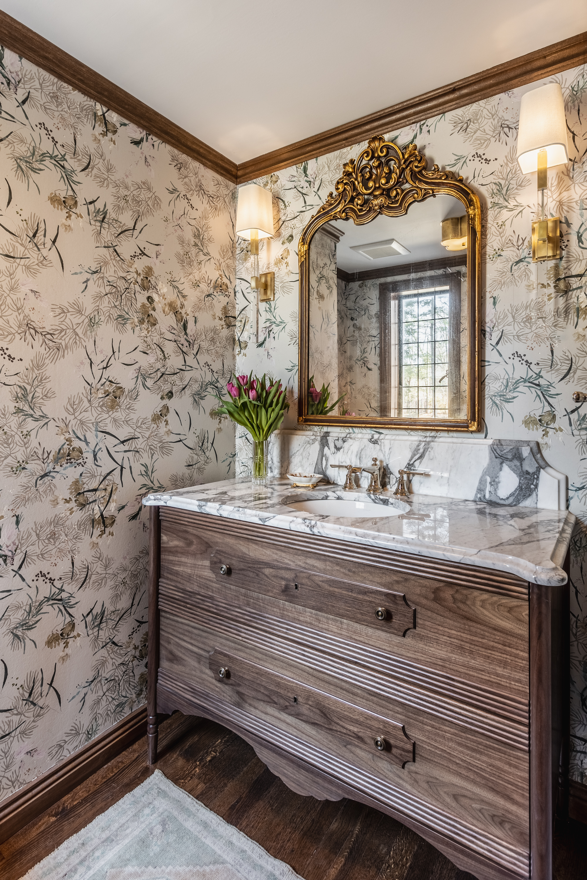 The powder room by Tiffany Skilling of Tiffany Skilling Interiors also has something of a woodland theme, thanks to the wallpaper and the vanity. Gold and polished marble, however, add sophistication. In fact, an ornate gold-frame mirror (like these) brings instant elegance to any space. (Find similar sconces here.)
